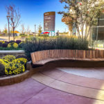 Curved cantilever Ogden bench next to garden at Grandscape mixed-use shopping center