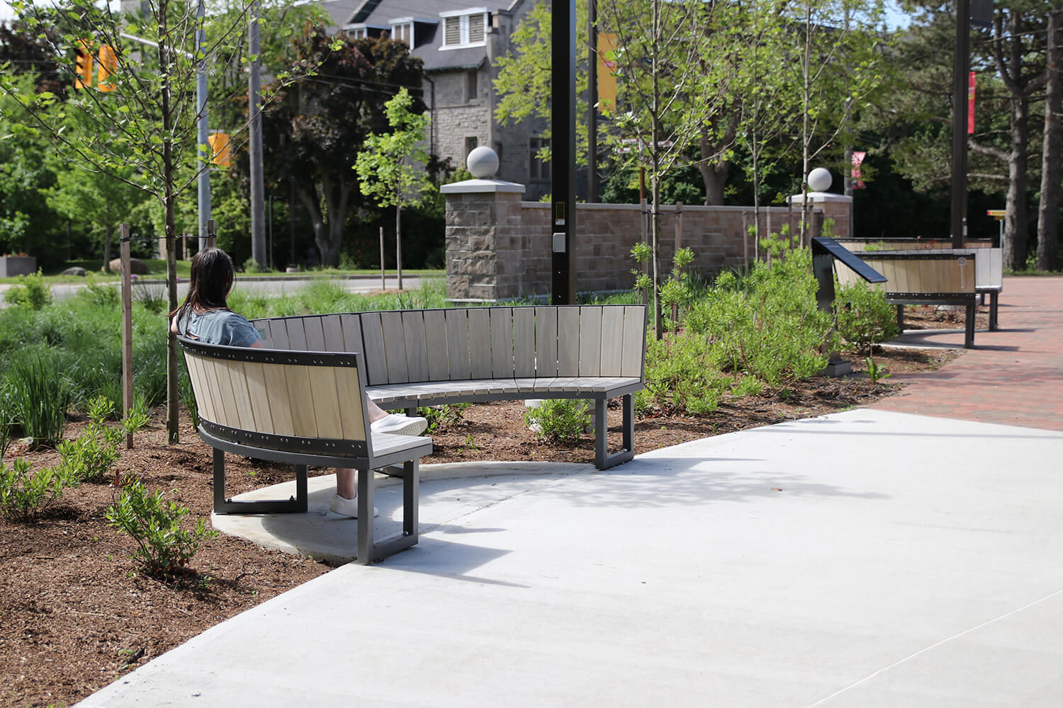 Student sitting on curved bench enjoying the outdoors on a sunny day at University of Guelph Lang Plaza