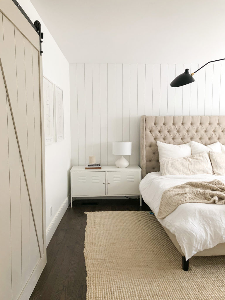 Sliding barn door in bedroom with white and beige accessories.