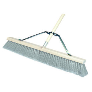 A large push broom with a wooden handle and grey synthetic bristles, identified as the "Large Metal Broom Brace for Push Brooms 24" - 48"," is shown against a white background.