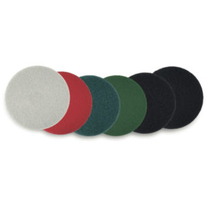 A 14" WHITE POLISHING FLOOR PAD, seen among six round abrasive pads in a variety of colors including light gray, red, two shades of green, and two shades of black, displayed on a white background.