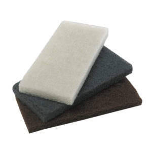 Three WHITE LIGHT DUTY UTILITY PADS from the 20 per case pack, in white, dark gray, and brown, are stacked on top of each other.