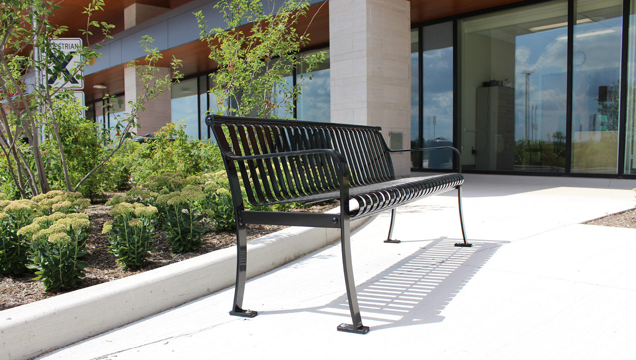 Metal bench with vertical slats outside 