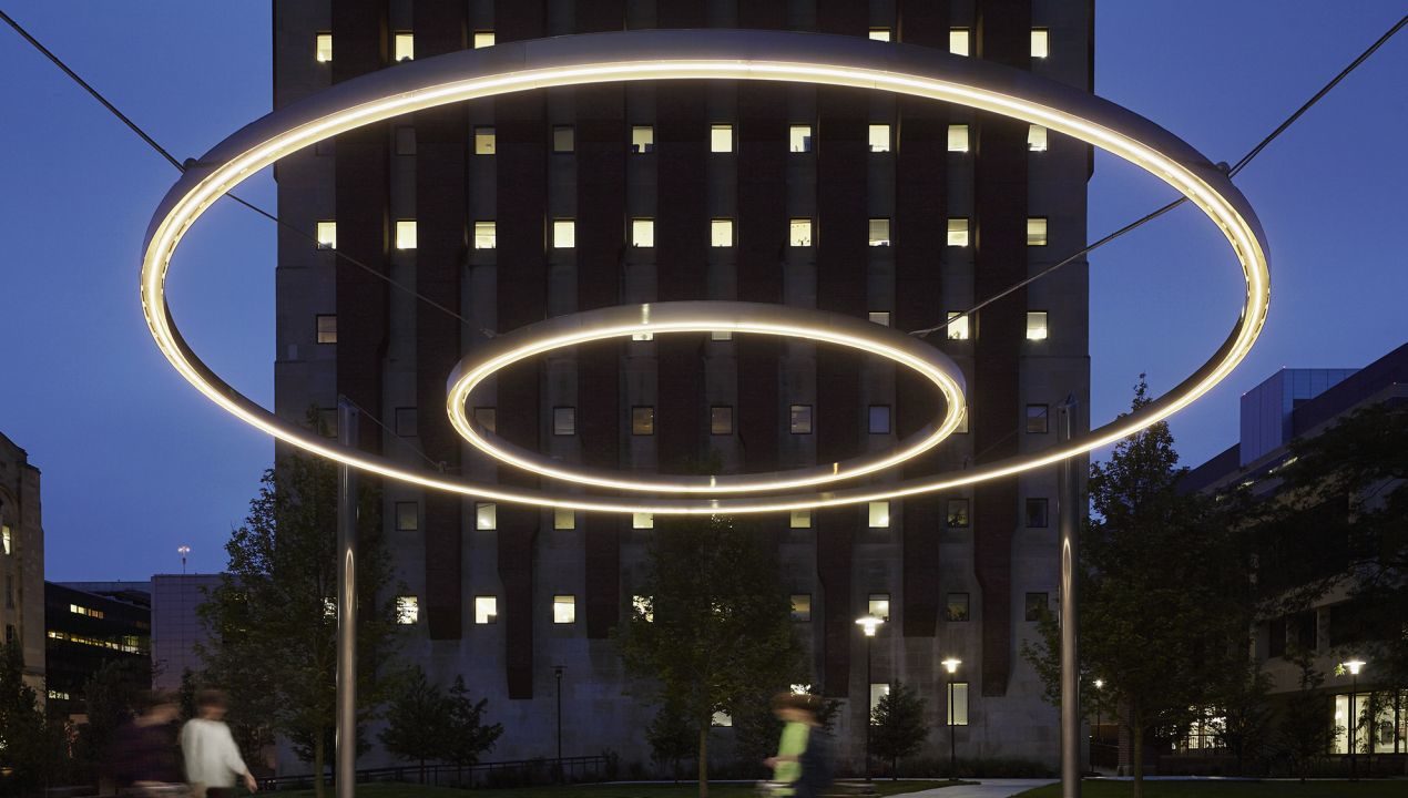 Circle of light suspended in sky with building behind
