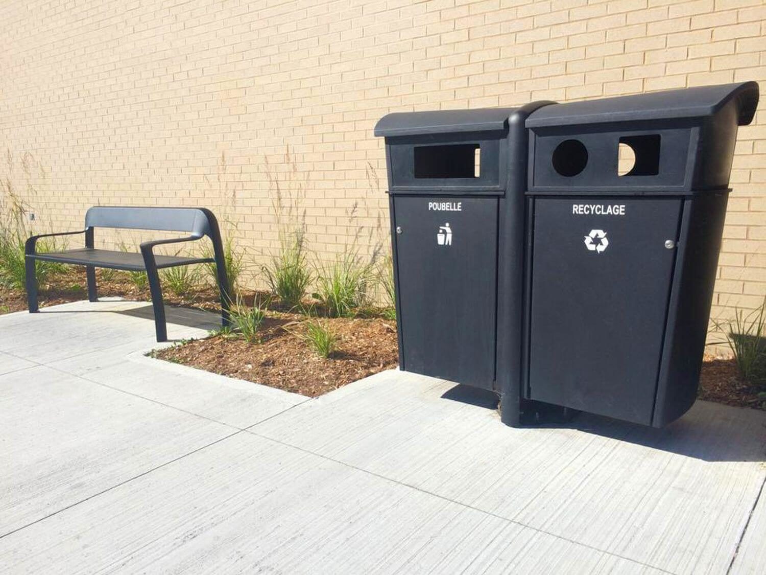 Two black bins next to a black bench