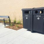 Two black bins next to a black bench