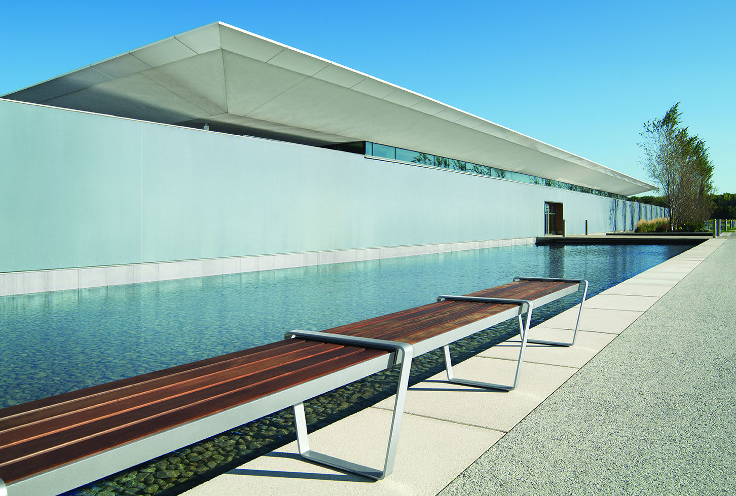 Straight wood Lexicon bench next to a modern building and a pool