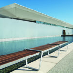 Straight wood Lexicon bench next to a modern building and a pool