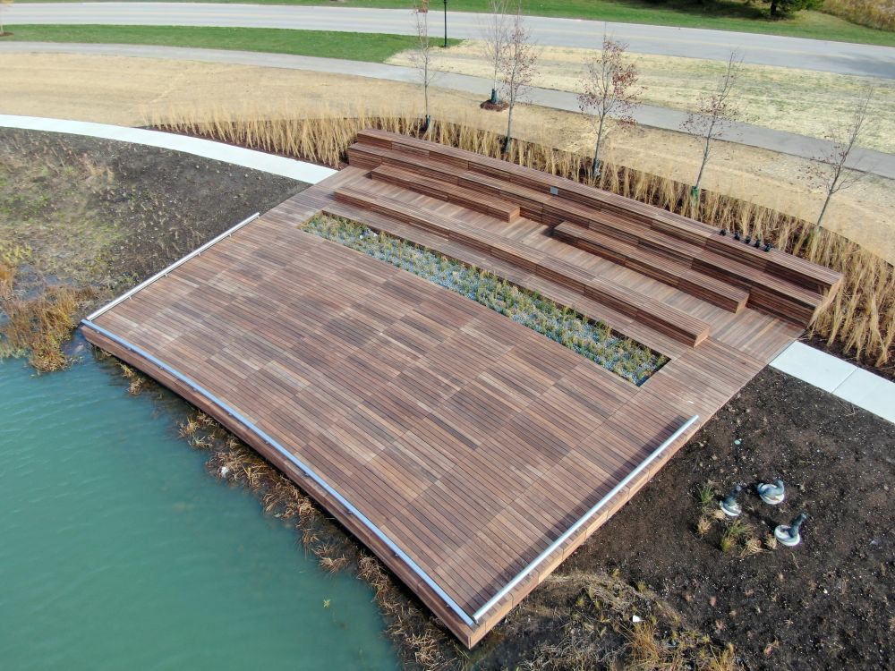 Custom Amphitheater, wooden stage next to water and greenery