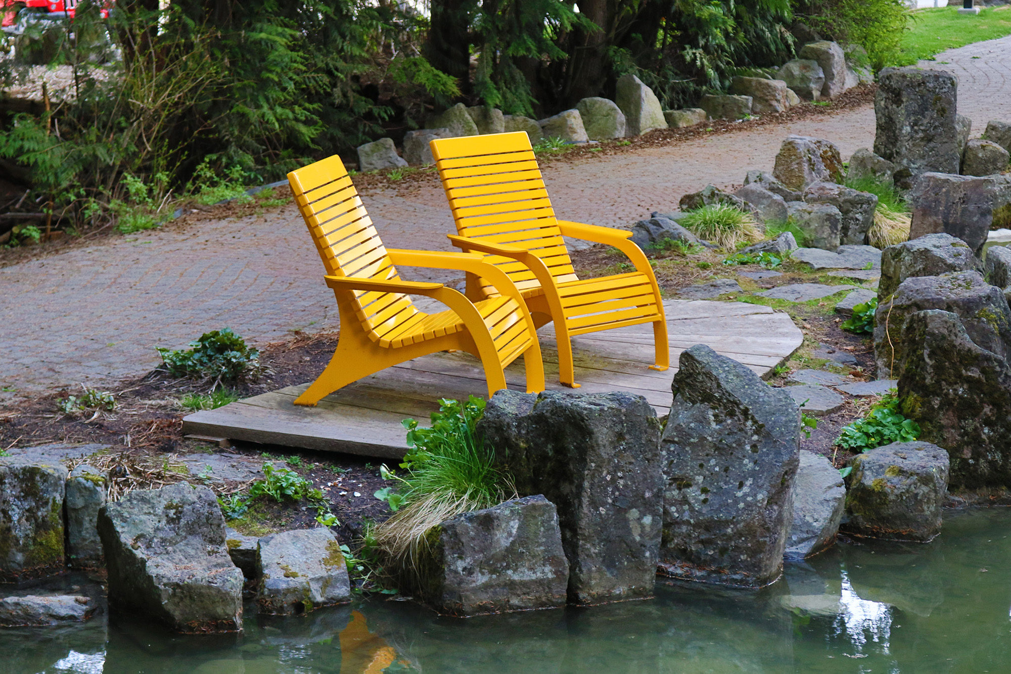 Yellow 720 Chairs surrounded by rocks and a pond