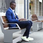 Man sitting on L-Series Backed Bench on city street