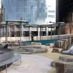 View of Battery Playscape with steel cloud canopies and curved bench. NYC buildings in the background