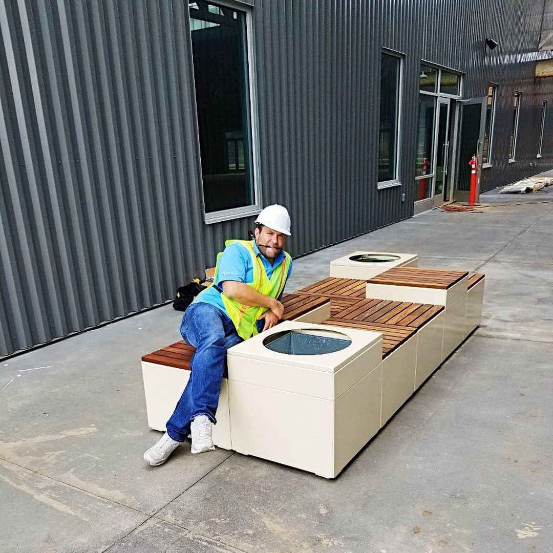A man in a hardhat and hi-vis safety vest leans on a newly-installed Pixel configuration.