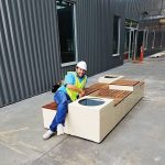 A man in a hardhat and hi-vis safety vest leans on a newly-installed Pixel configuration.