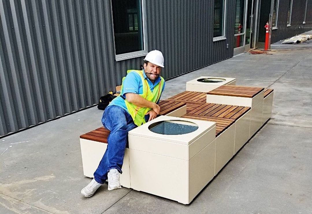 A man in a hardhat and hi-vis safety vest leans on a newly-installed Pixel configuration.