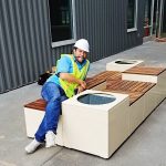 A man in a hardhat and hi-vis safety vest leans on a newly-installed Pixel configuration.