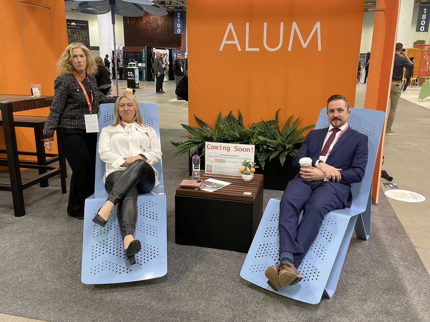 Members of the Maglin sales team recline on the ALUM Chaise lounge at ASLA 2023 in Minneapolis.