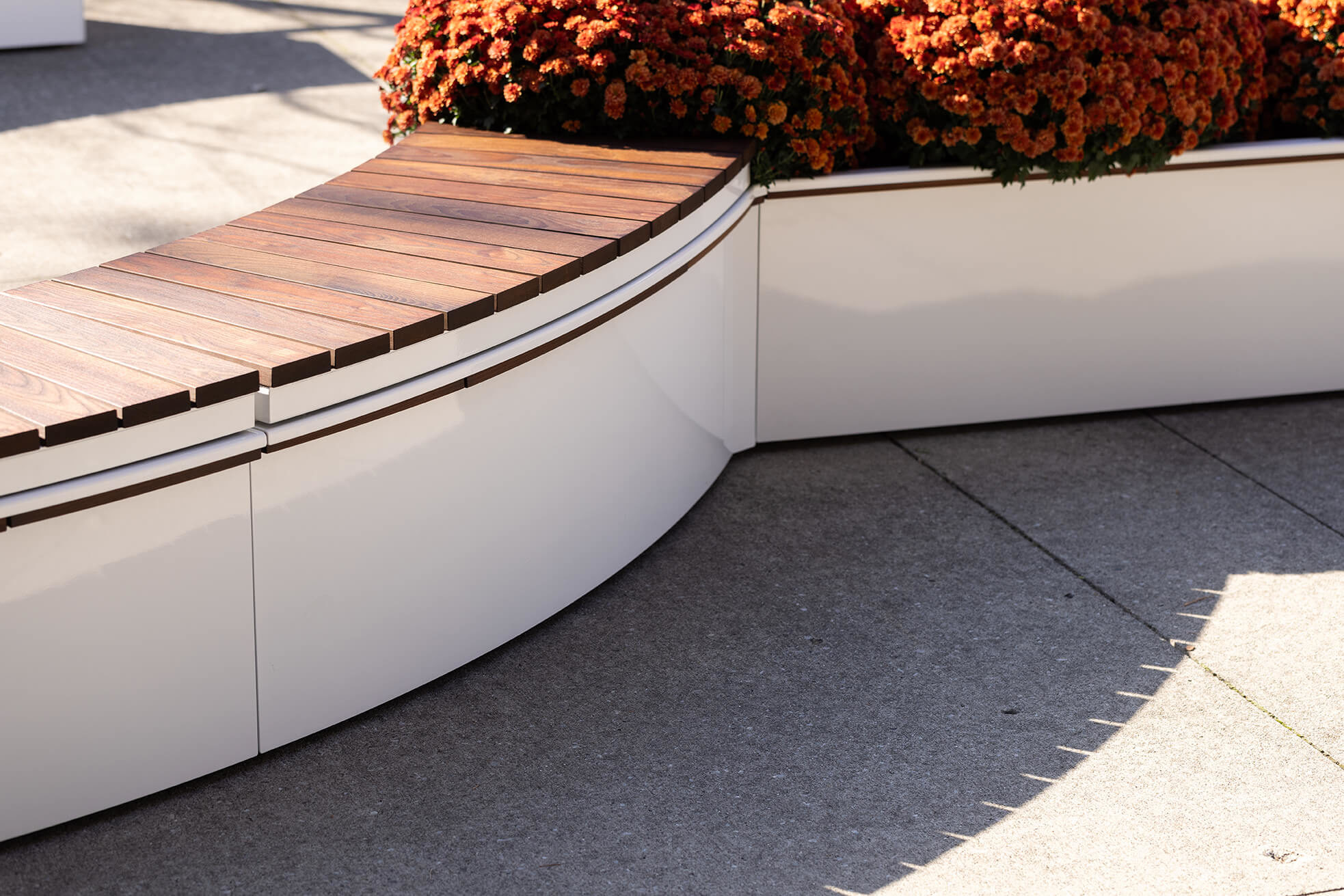 maglin-white-canoe-curve White powdercoated CANOE modular planters with Ogden bench seating and orange mums