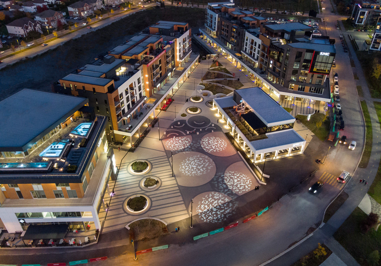 A drone image of the AGORA mixed use development at night. Seating is underlit by LEDs and circular spotlights light up the square.