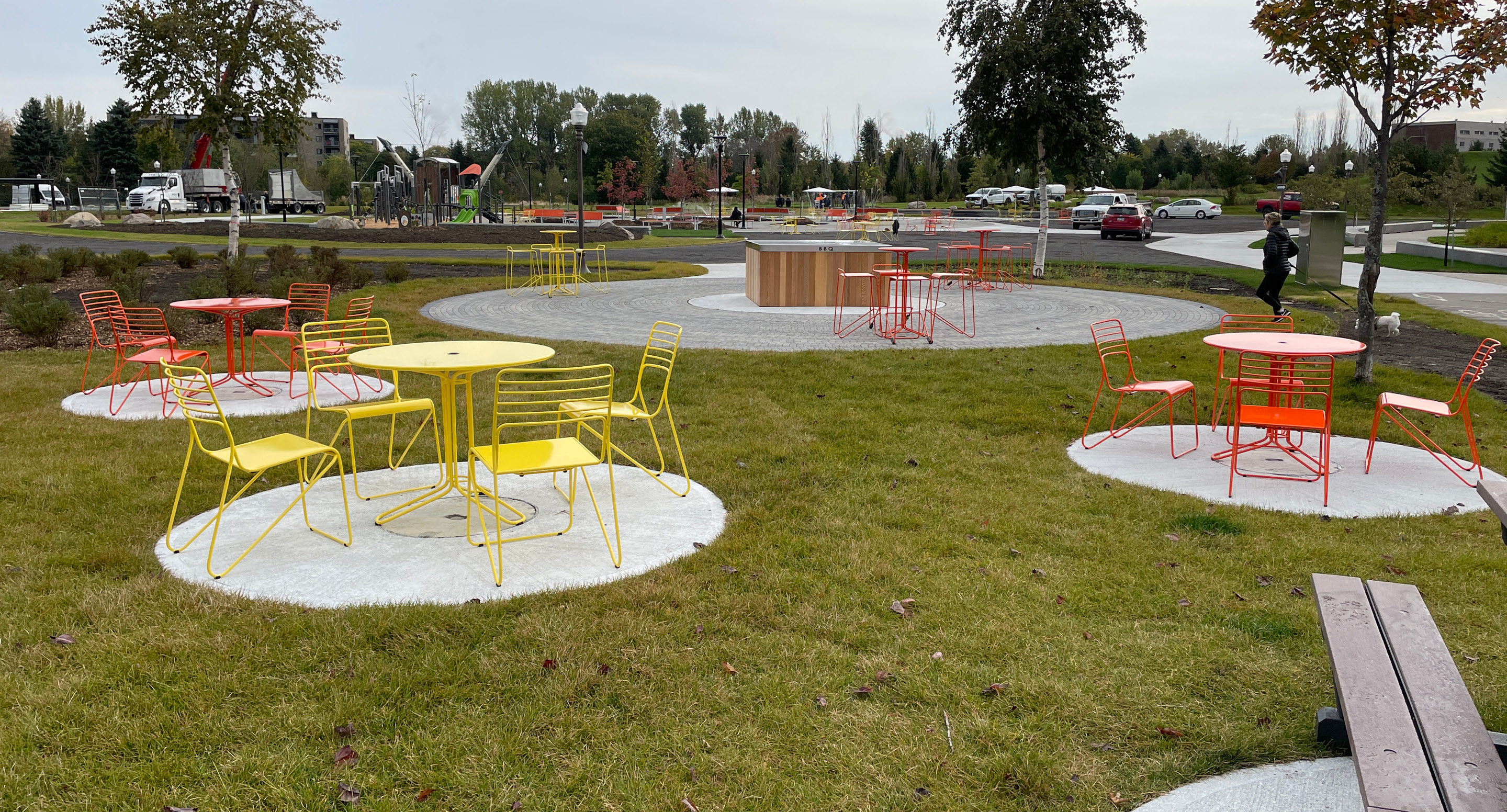 maglin-collections-kontur-hero Yellow and orange Kontur chairs and cafe tables in a park setting