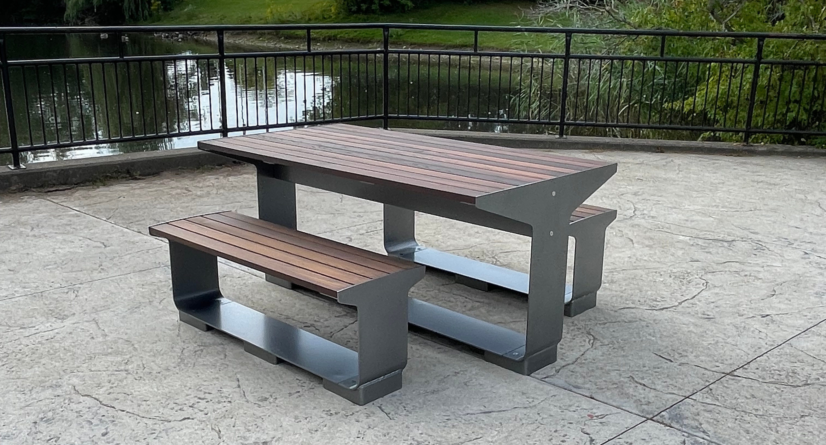 L-Series table with backless benches in wood on patio next to pond and fence