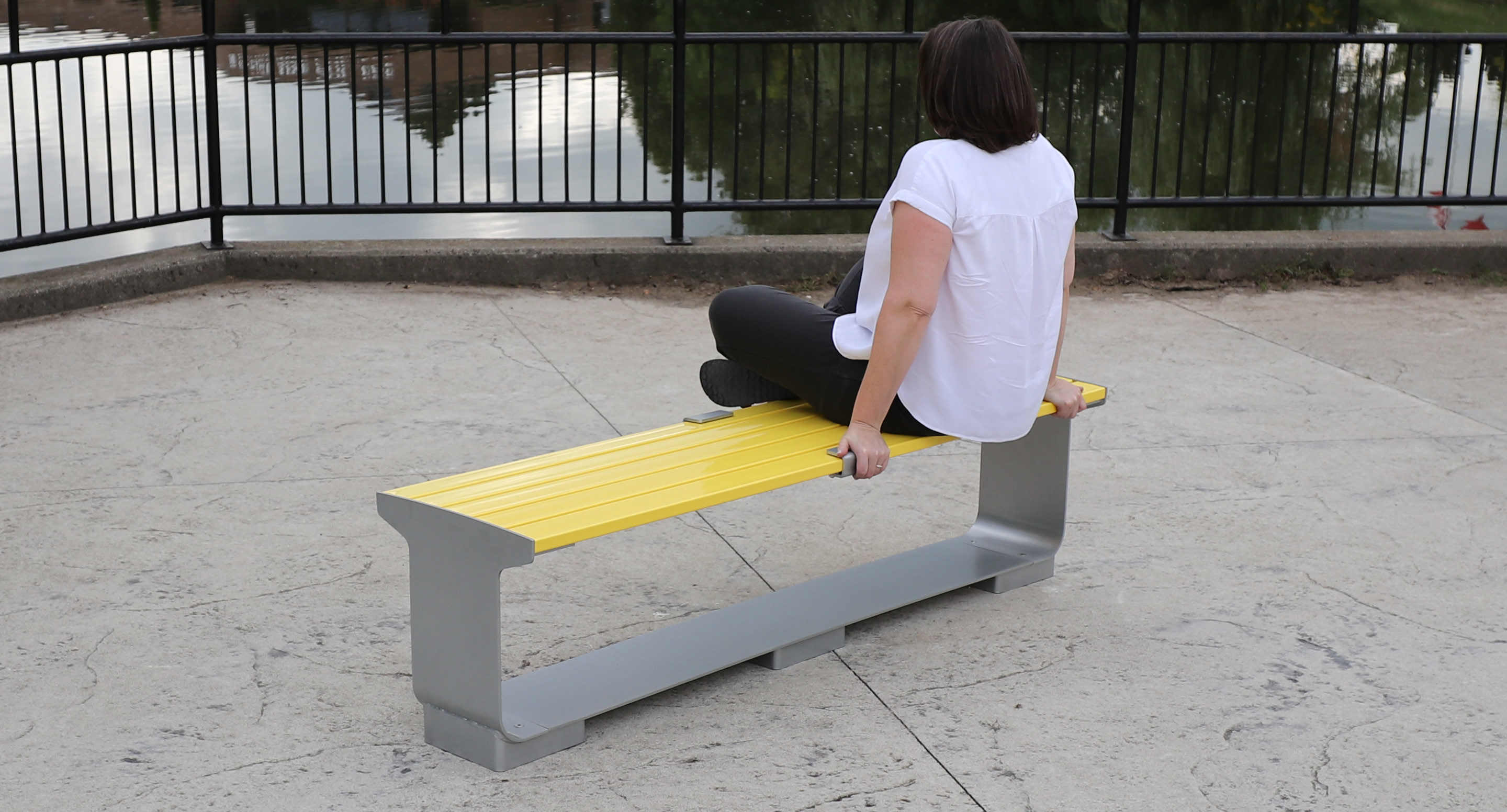 maglin-collections_l-series-car5 Women sitting on backless yellow L-Series bench on patio next to water and fence
