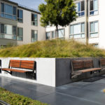 Wall-mount benches attached to large concrete planter within apartment complex