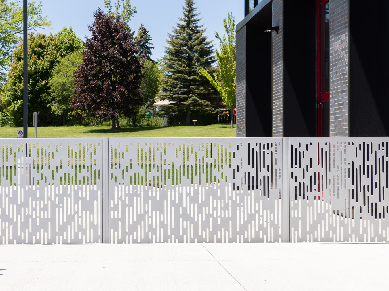 FLEXX panels with matrix pattern powdercoated silver next to building and trees
